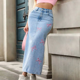 Person wearing light blue jeans with pink bows, standing against a building.
